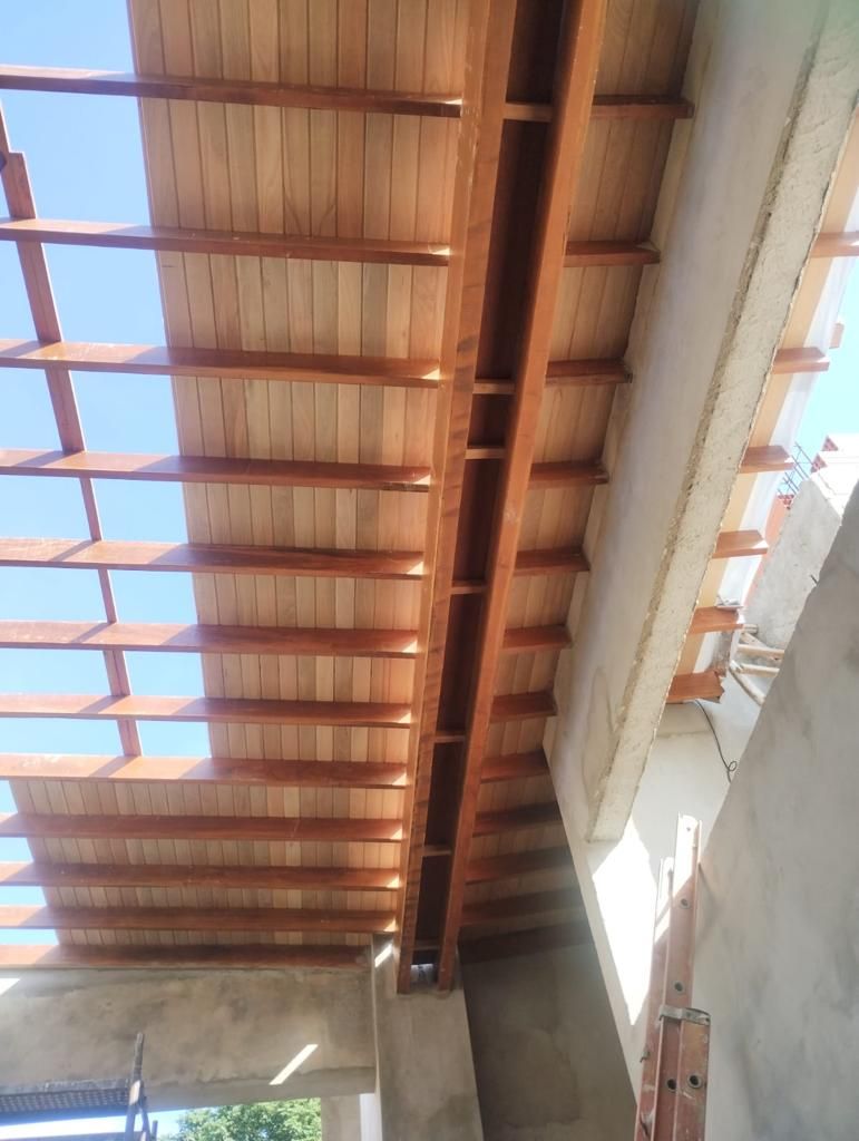 Estrutura de teto de varanda em madeira com vigas expostas.