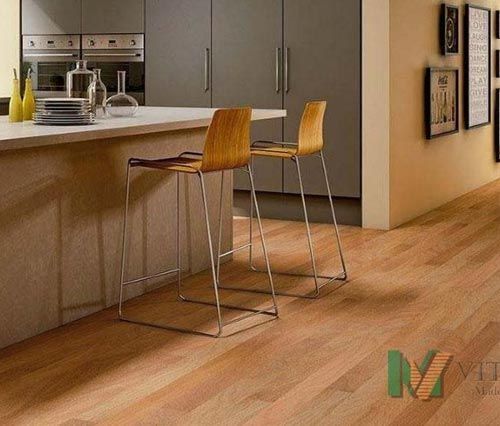 Cozinha com piso de madeira, ilha com banquetas e armários escuros.