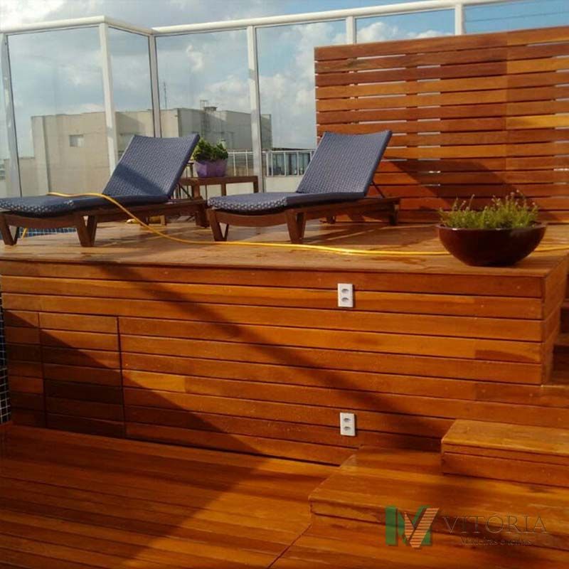 Terraço de madeira na cobertura com espreguiçadeiras e divisória para privacidade.