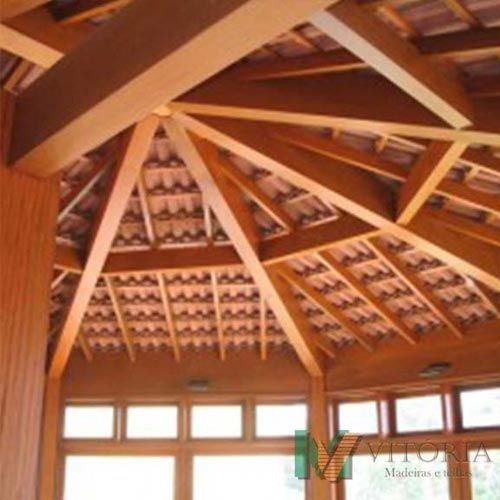 Teto de pavilhão de madeira com vigas expostas e cobertura de telhas.