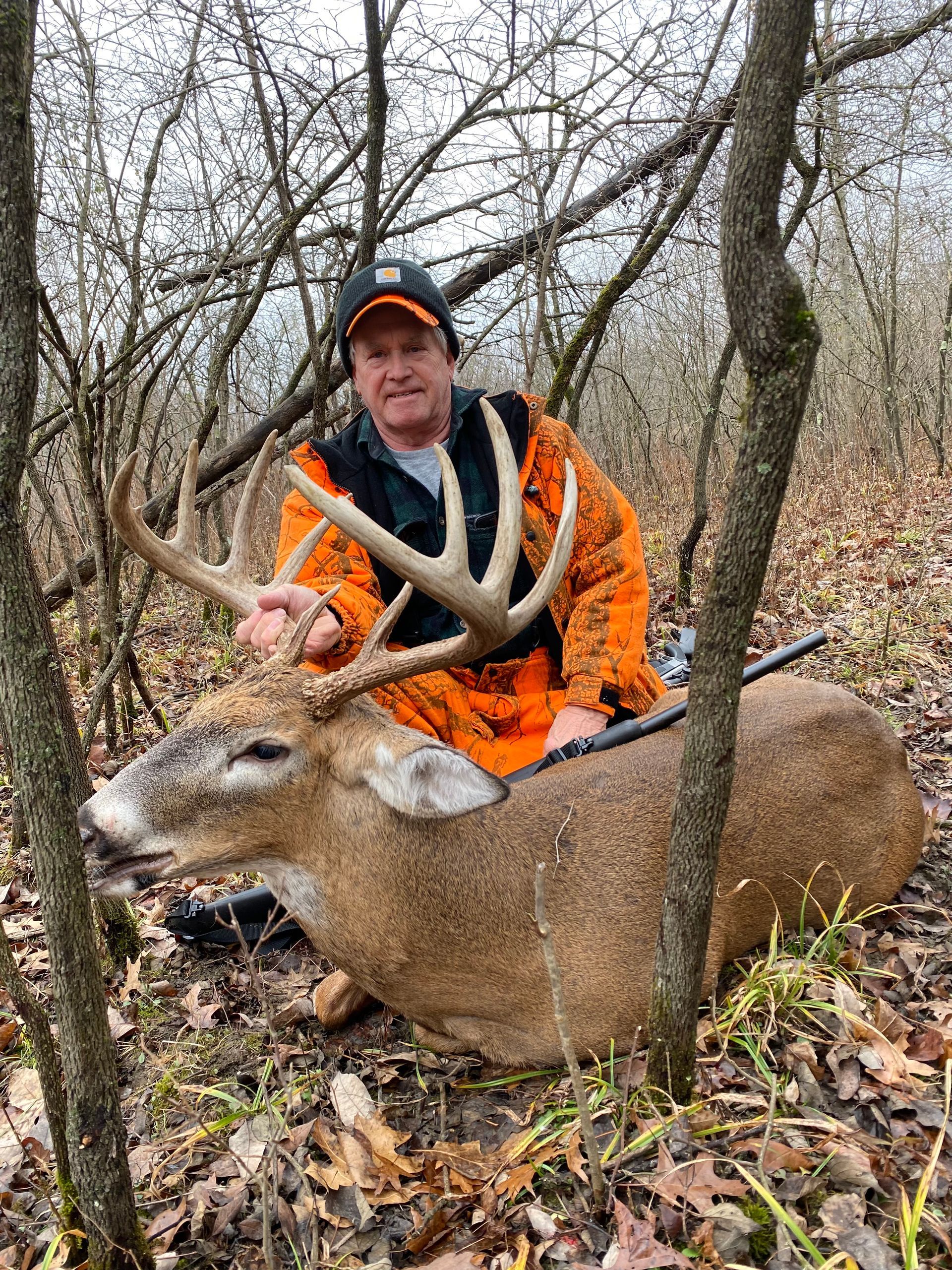 A man is sitting on top of a deer in the woods.