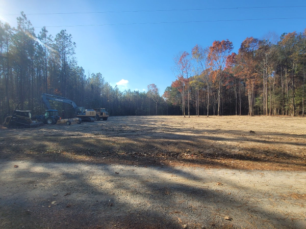 A large dirt field with trees in the background on a sunny day.