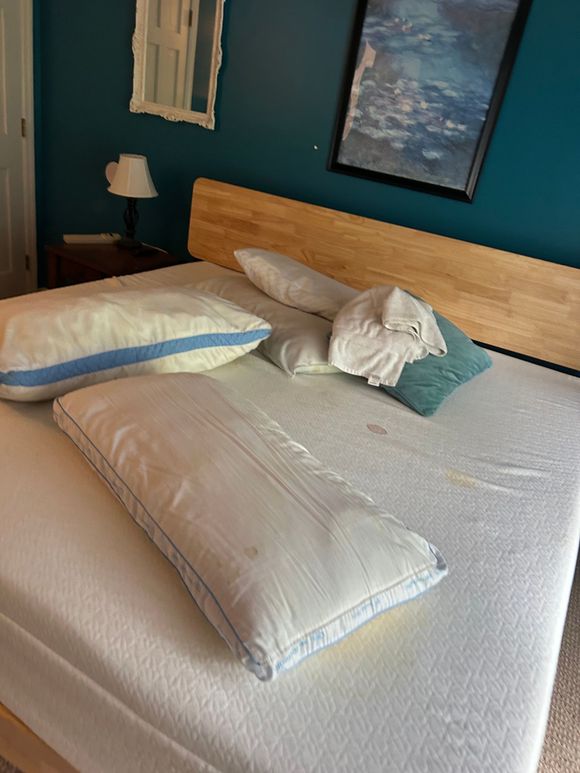 A bed with a wooden headboard and pillows on it in a bedroom.