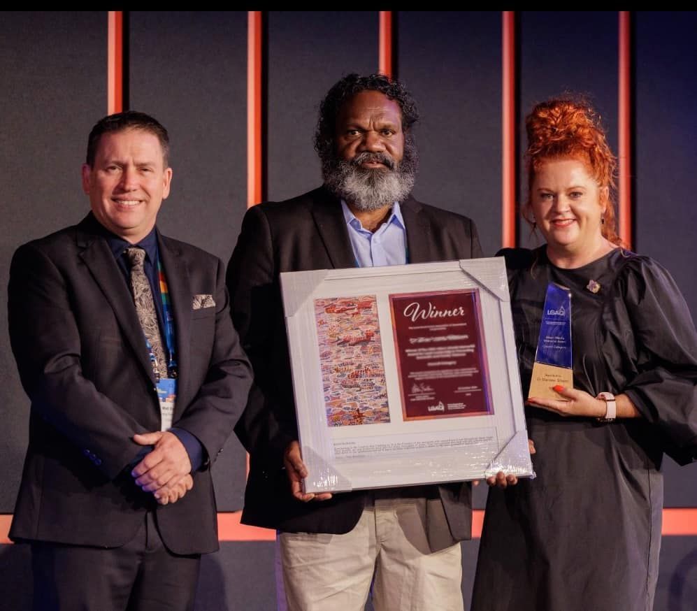 A man in a suit is holding a framed certificate that says winners