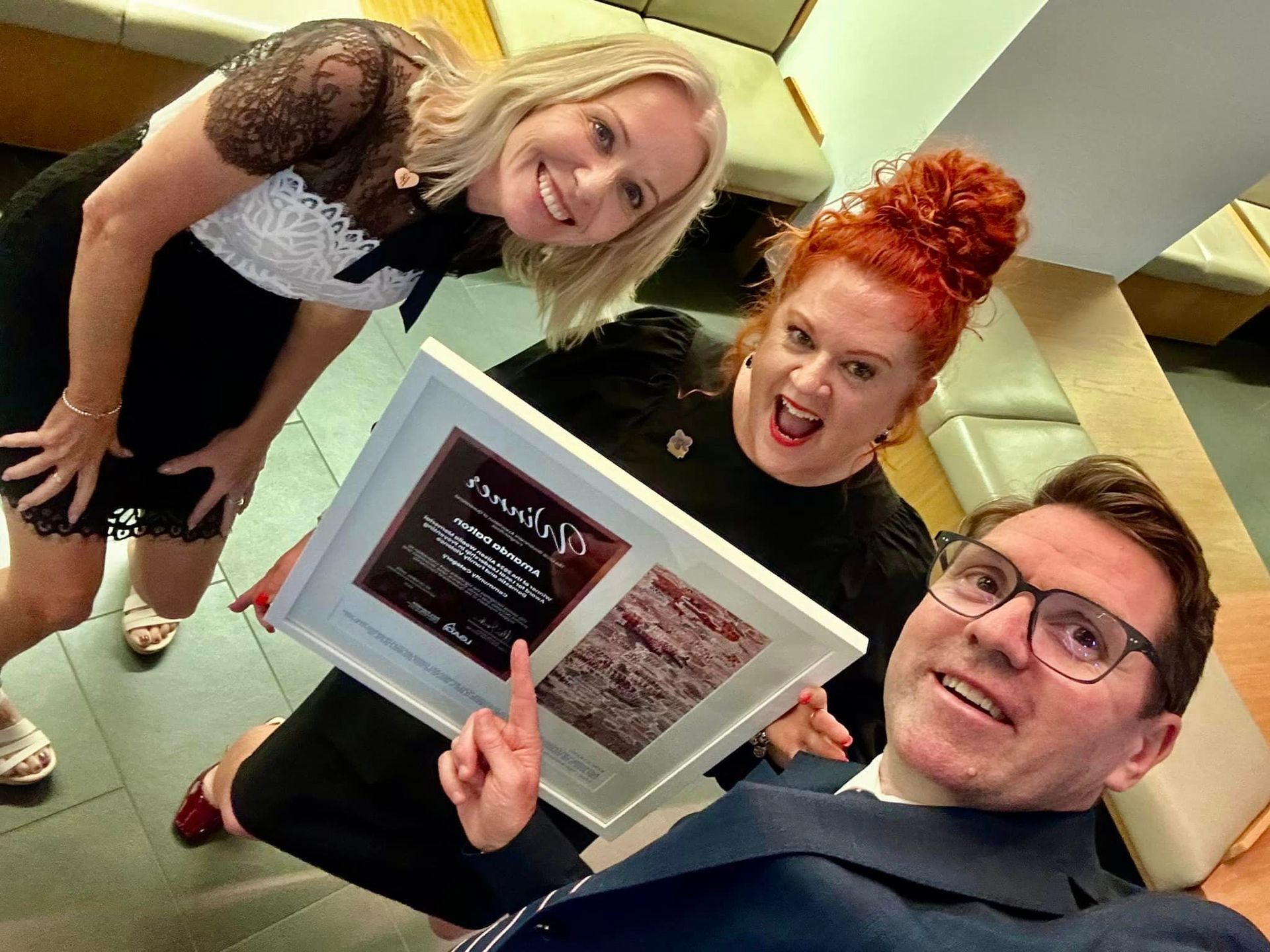 A man and two women are holding a framed certificate.