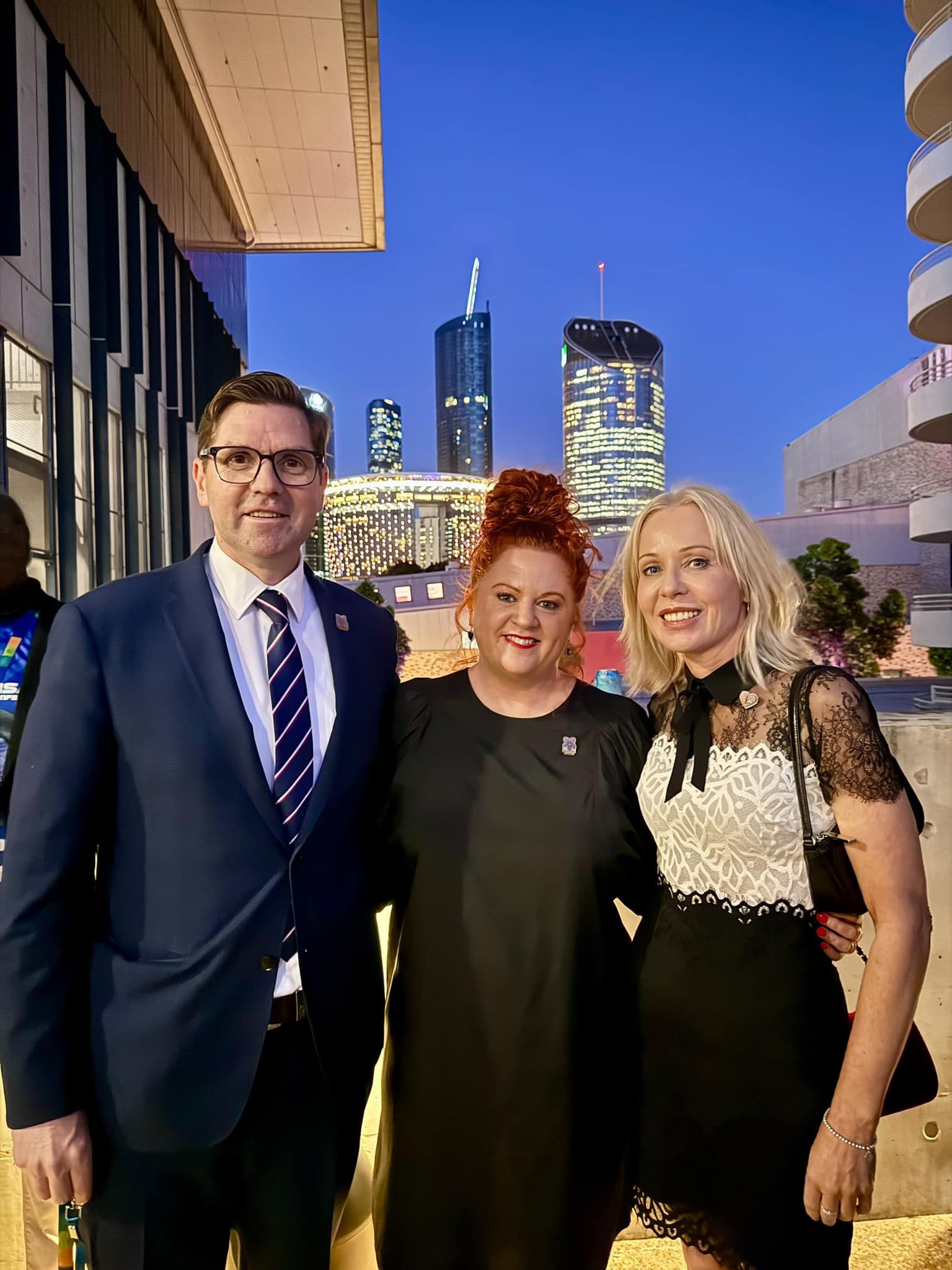 A man in a suit and tie is posing for a picture with two women.