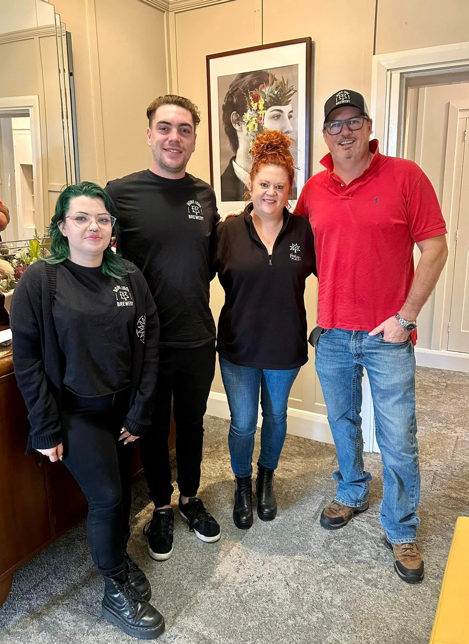 A group of people from Bone Idol Brewery are posing for a picture in a room at Protea Place.