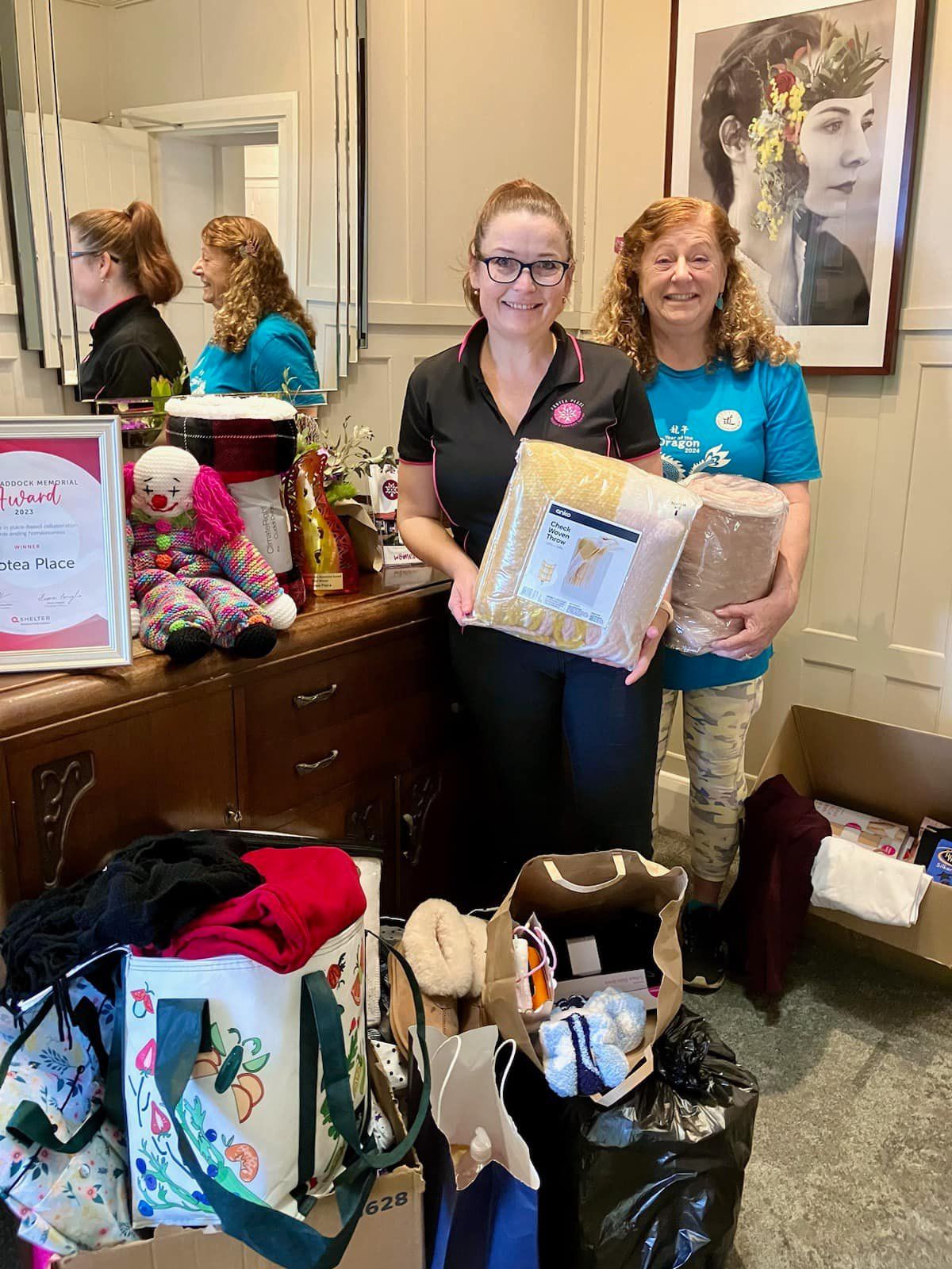 Two women are standing next to each other in a room holding boxes.