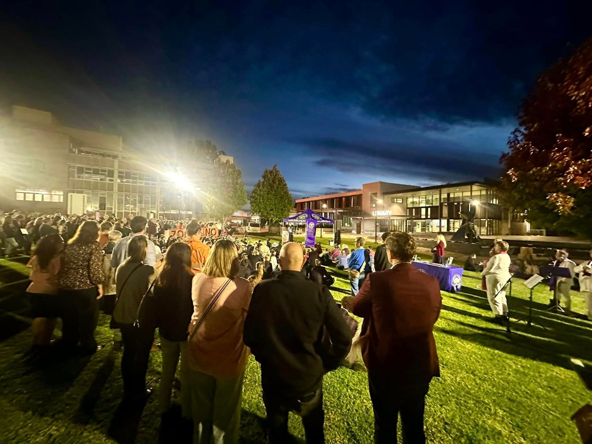 A group of people are standing in a park at night.