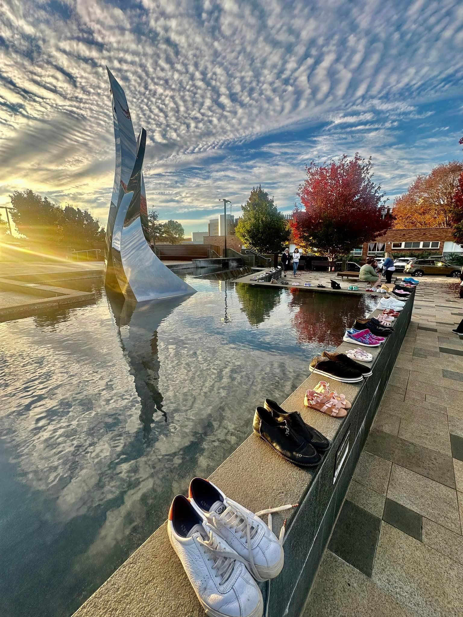 A row of shoes are sitting next to a water feature.