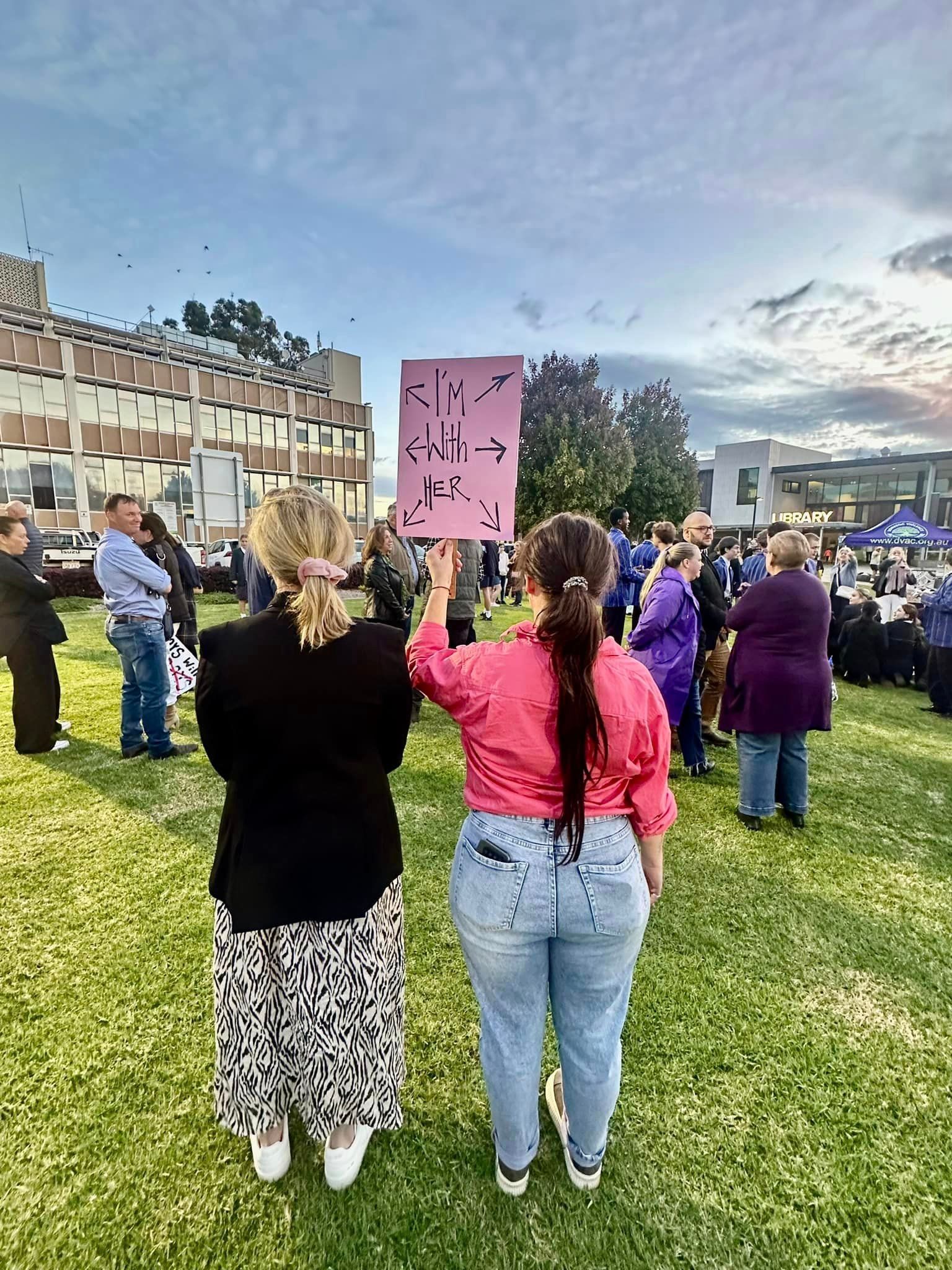 A group of people are standing in a grassy field holding signs.