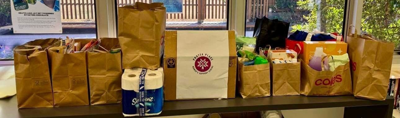 A row of brown paper bags filled with groceries are sitting on a table.