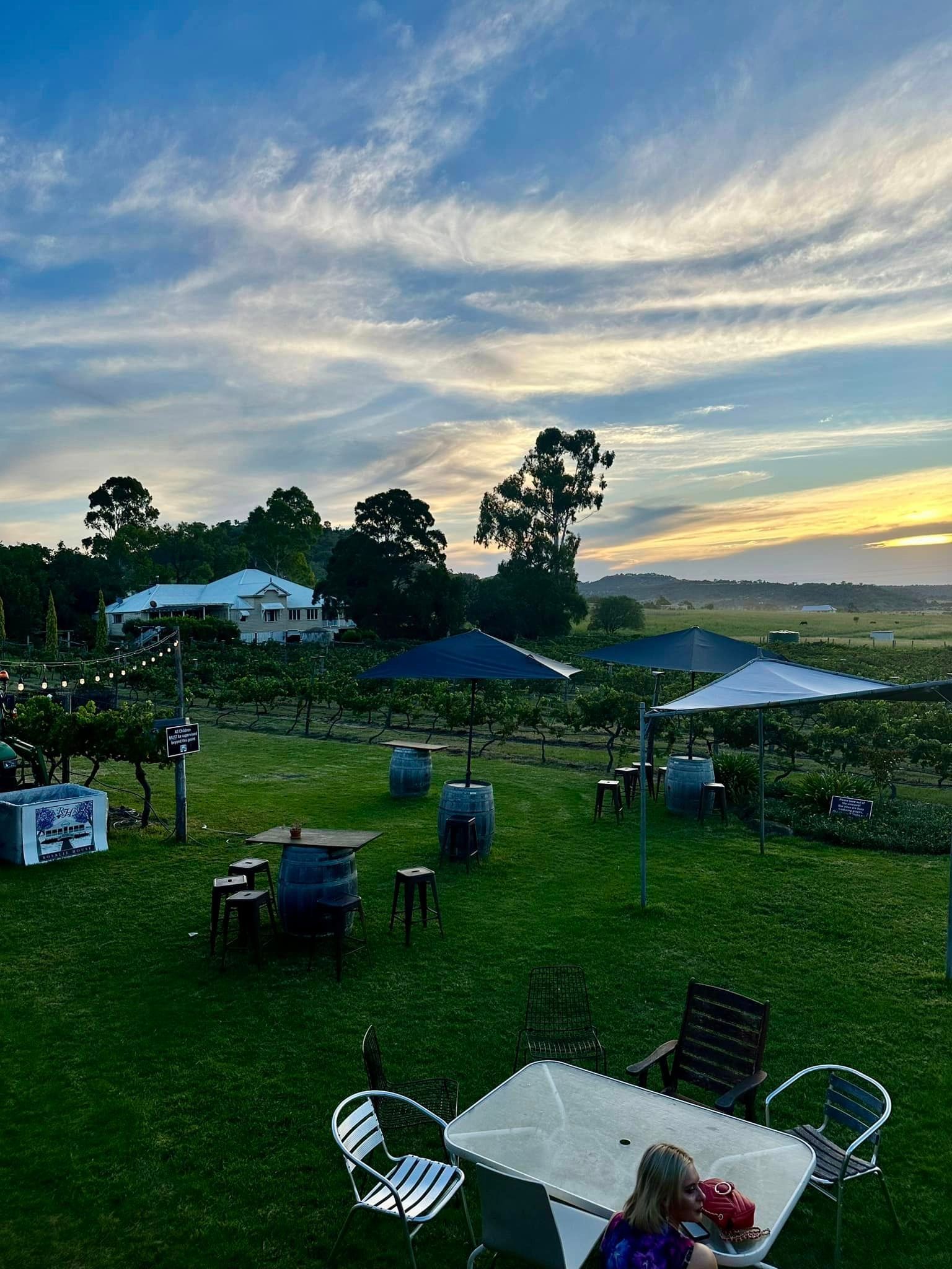 A woman is sitting at a table in a field.