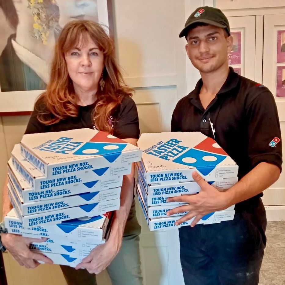 A man and a woman are holding boxes of domino 's pizza