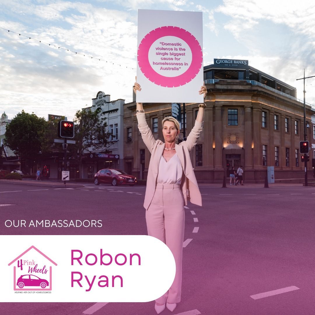 A woman in a pink suit is holding a sign that says robon ryan