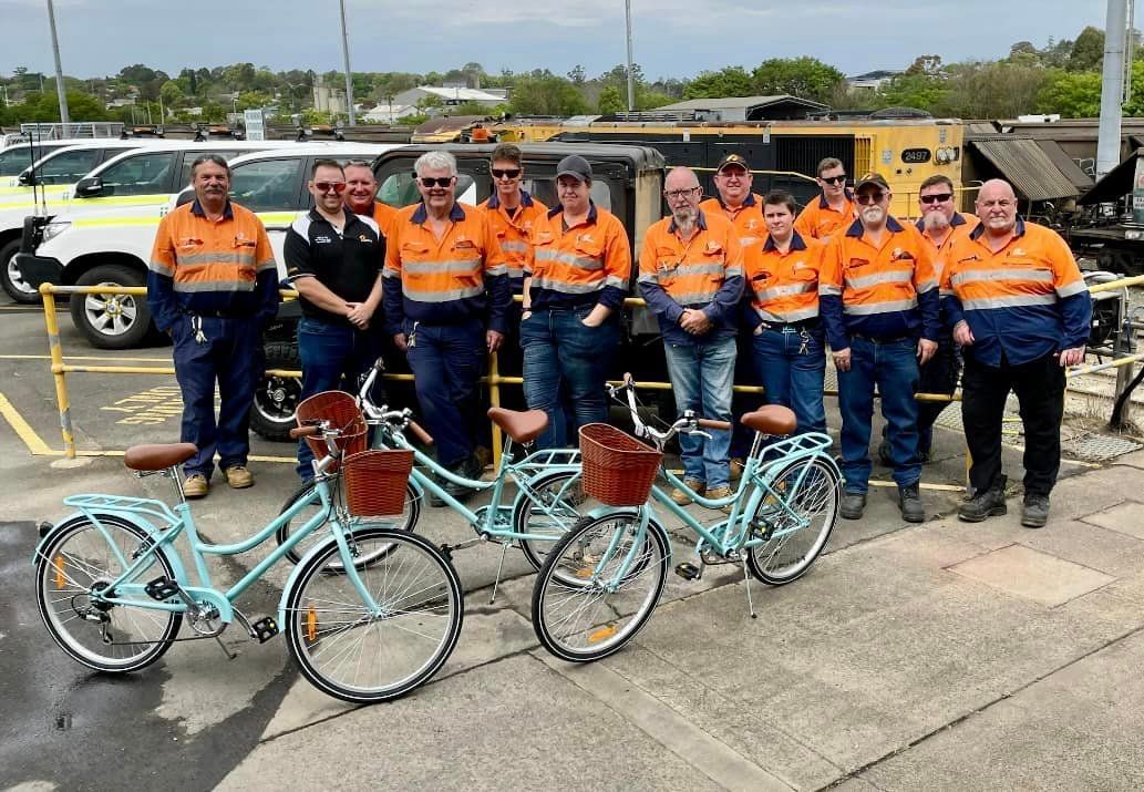A group of men from Aurizon are standing next to bicycles.
