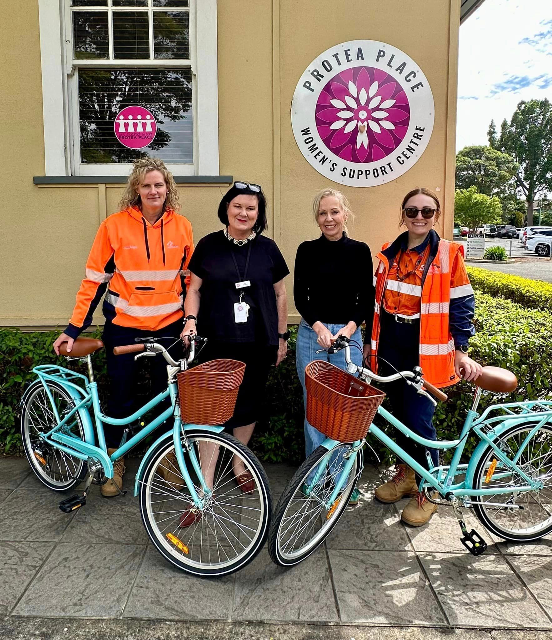 A group of people standing next to bicycles in front of a building.