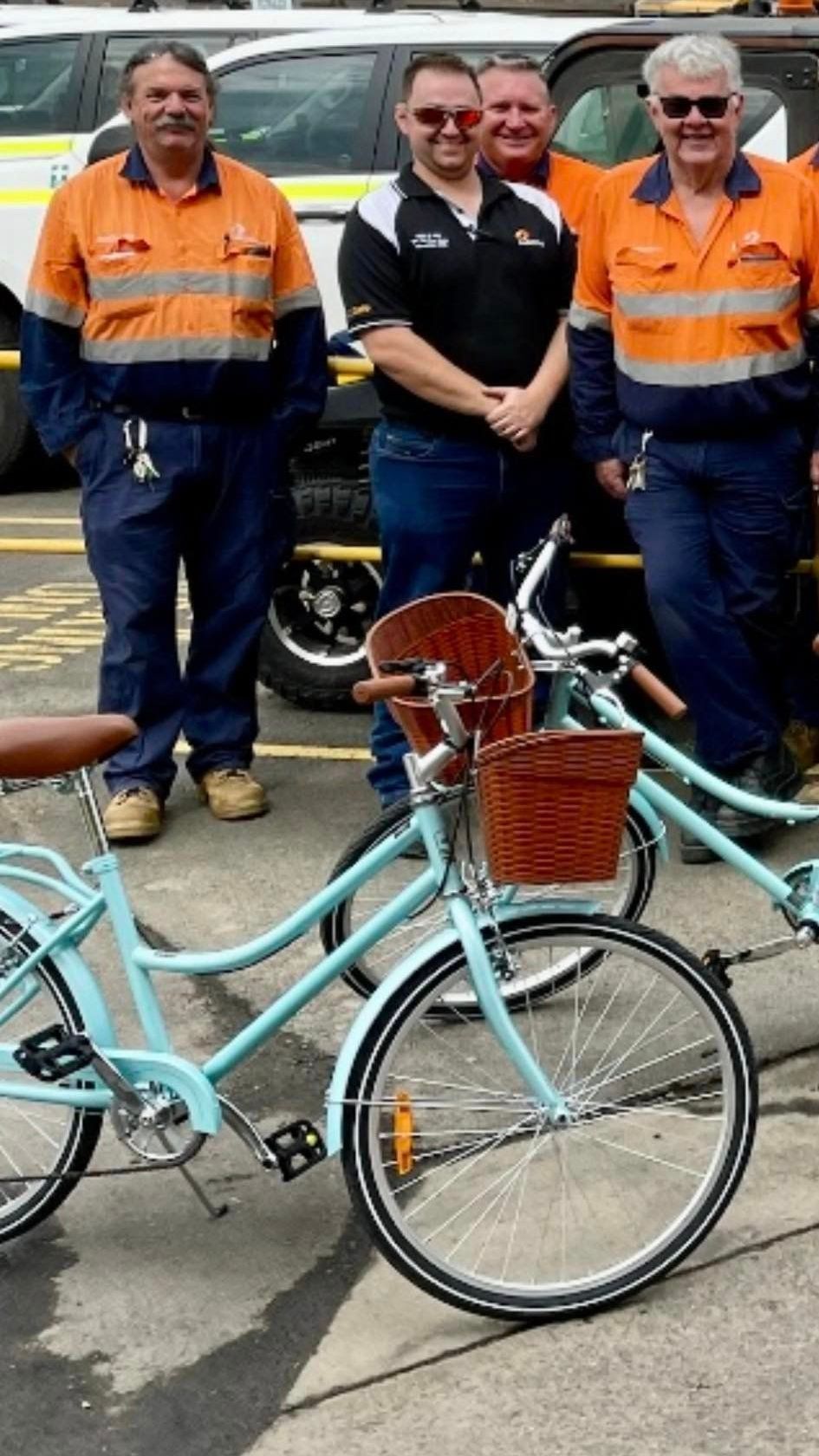 A group of men from Aurizon are standing next to bicycles.
