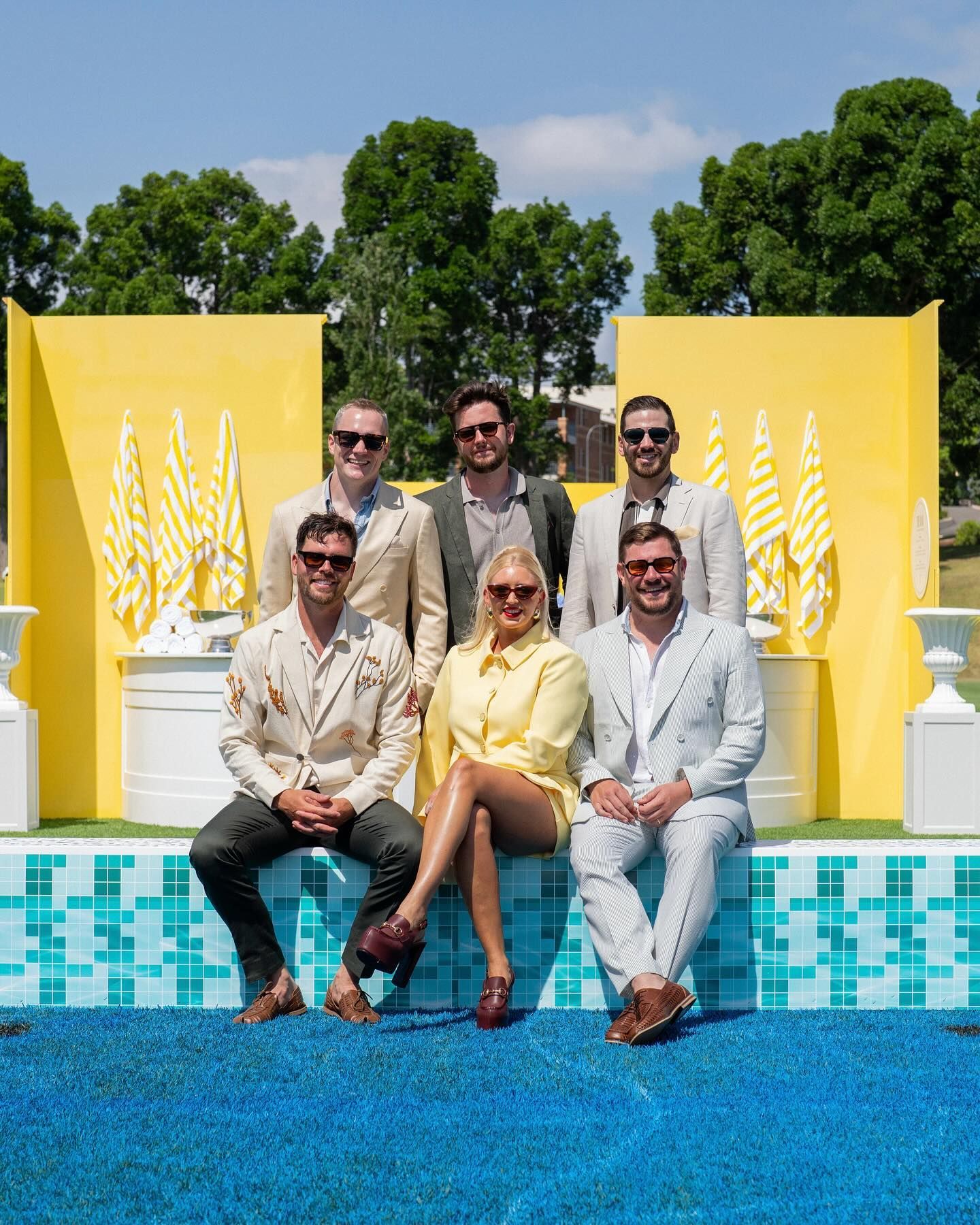 A group of people are posing for a picture in front of a yellow wall.