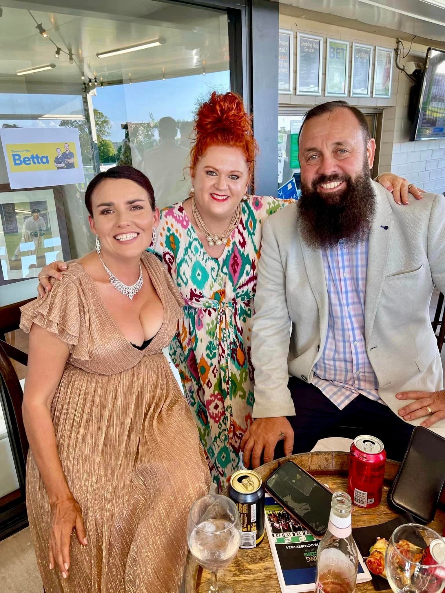 A man and two women are posing for a picture while sitting at a table.