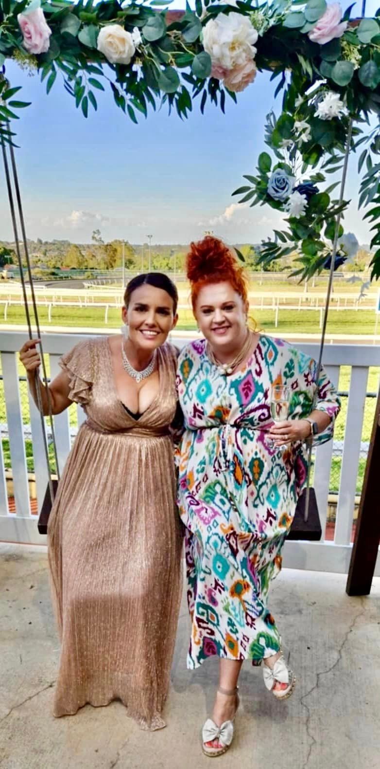 Two women are posing for a picture while sitting on a swing.