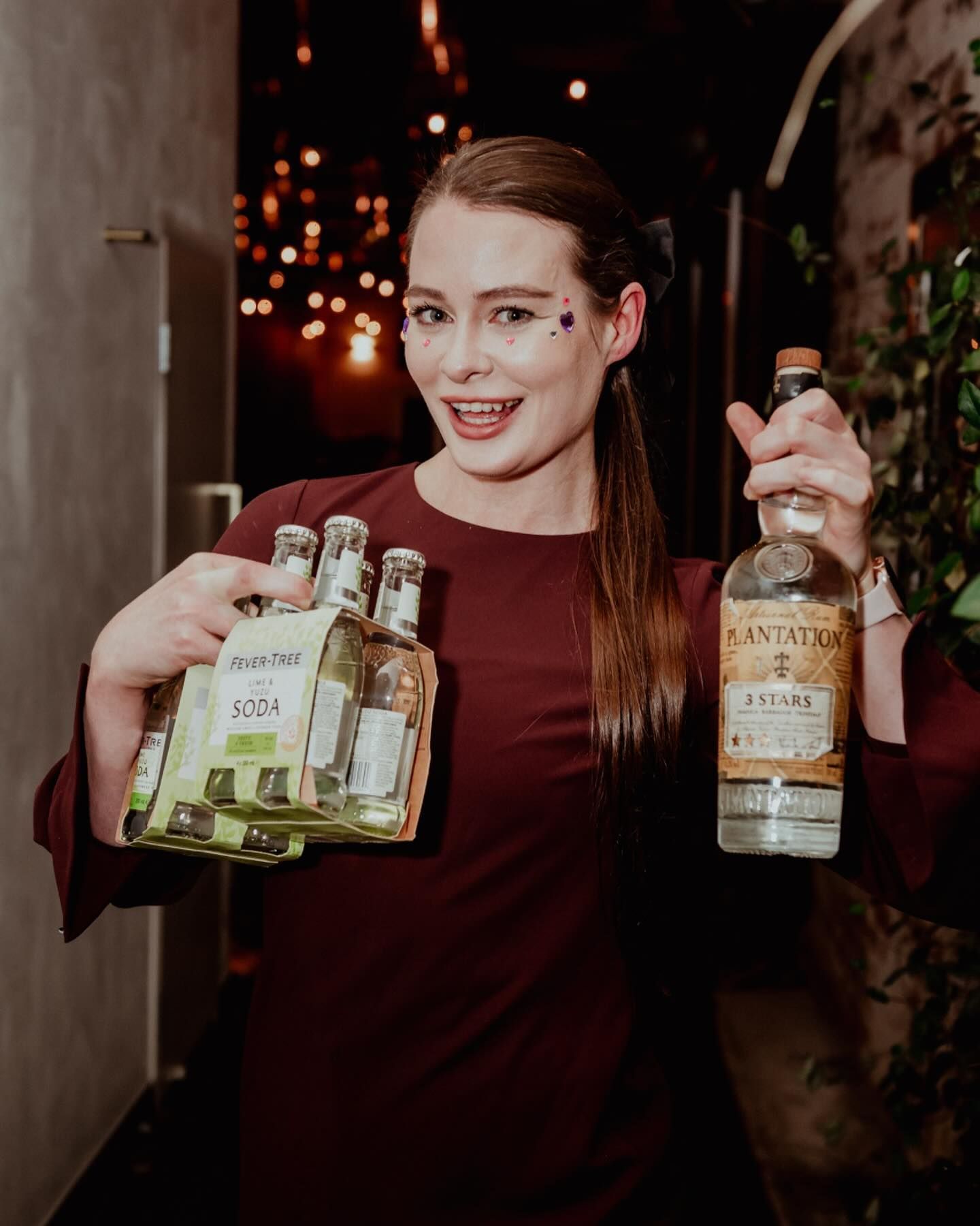A woman is holding a bottle of tequila and a pack of tequila.