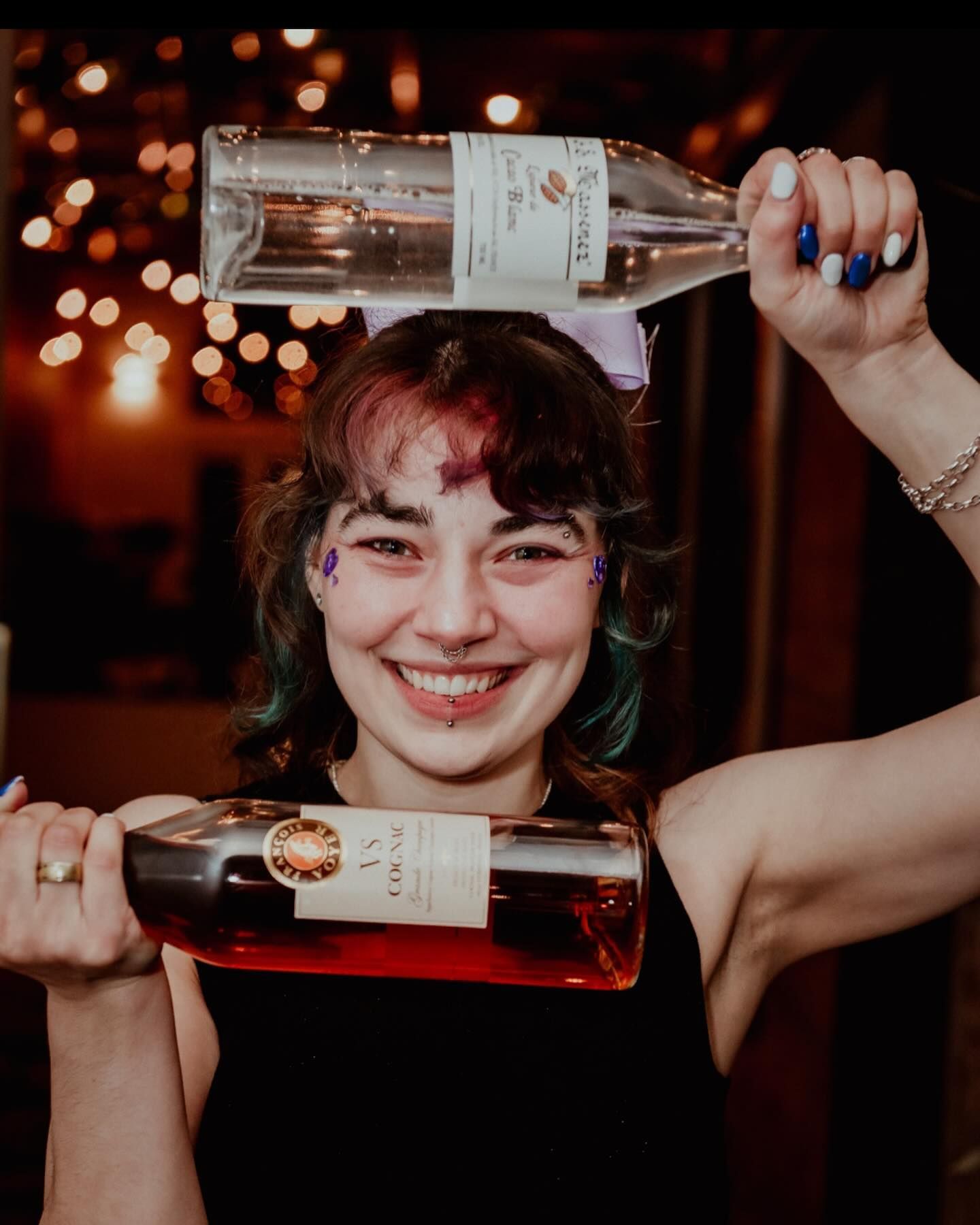 A woman is holding a bottle of wine on her head