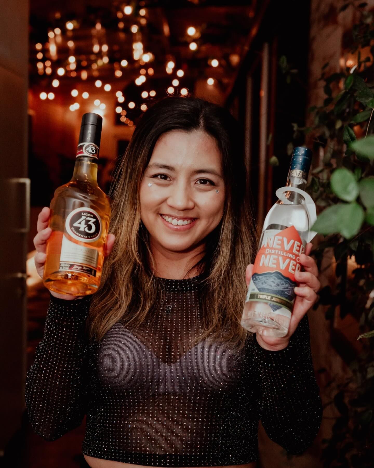A woman is holding two bottles of alcohol in her hands.