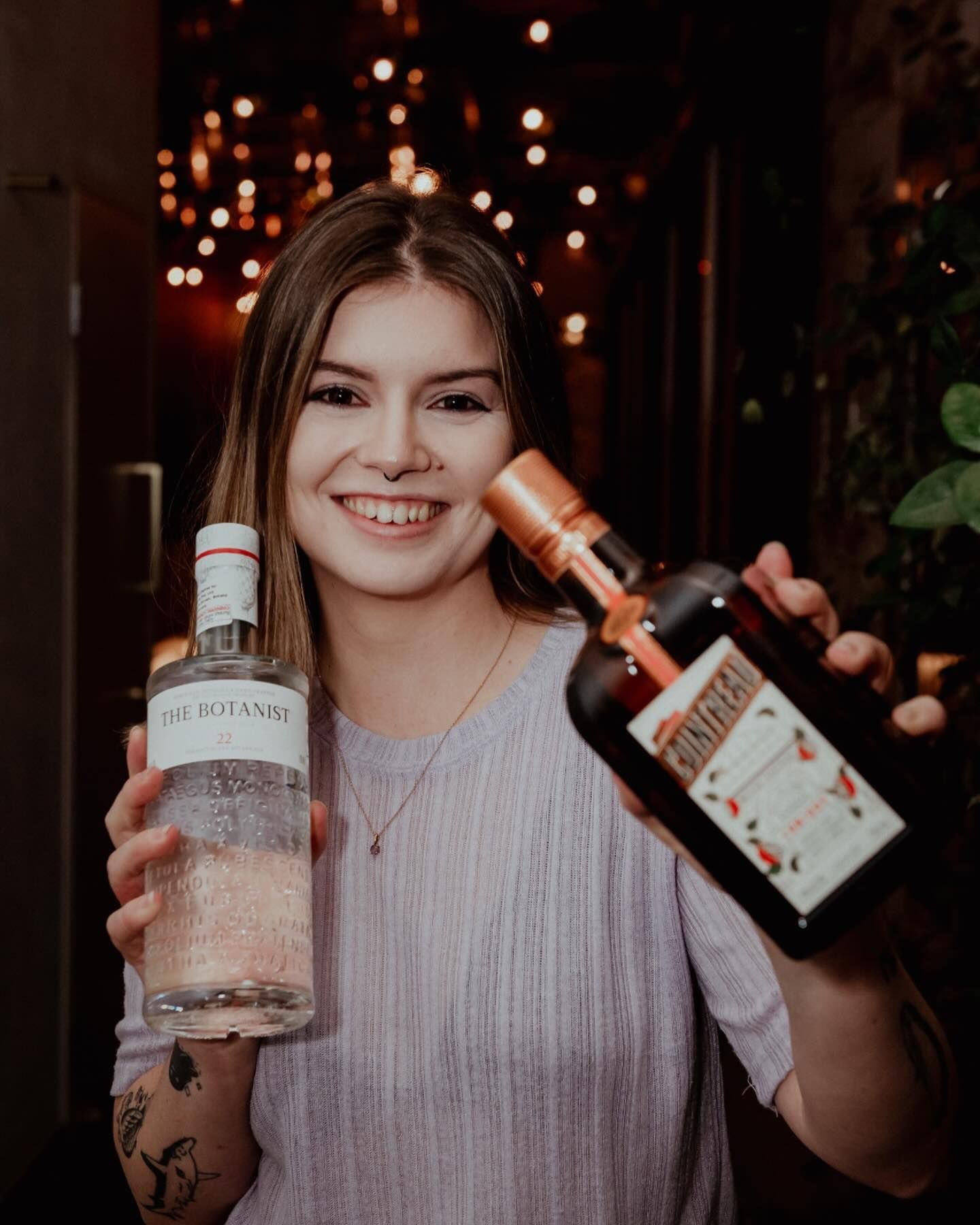 A woman is holding two bottles of alcohol in her hands.