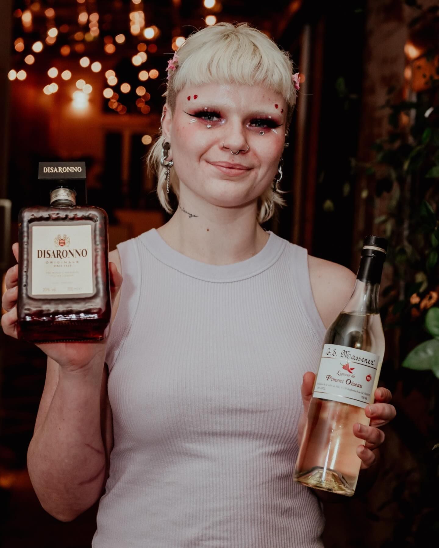A woman is holding a bottle of cognac and a bottle of wine.