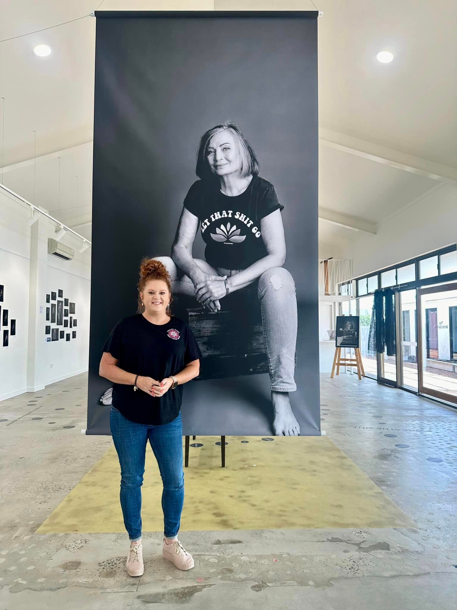 A woman is standing in front of a large black and white photo of a woman.