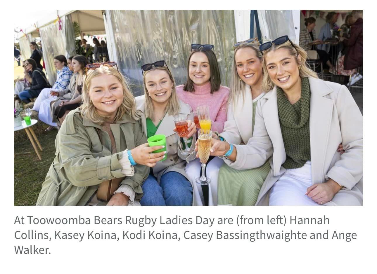 A group of women are sitting next to each other holding drinks.