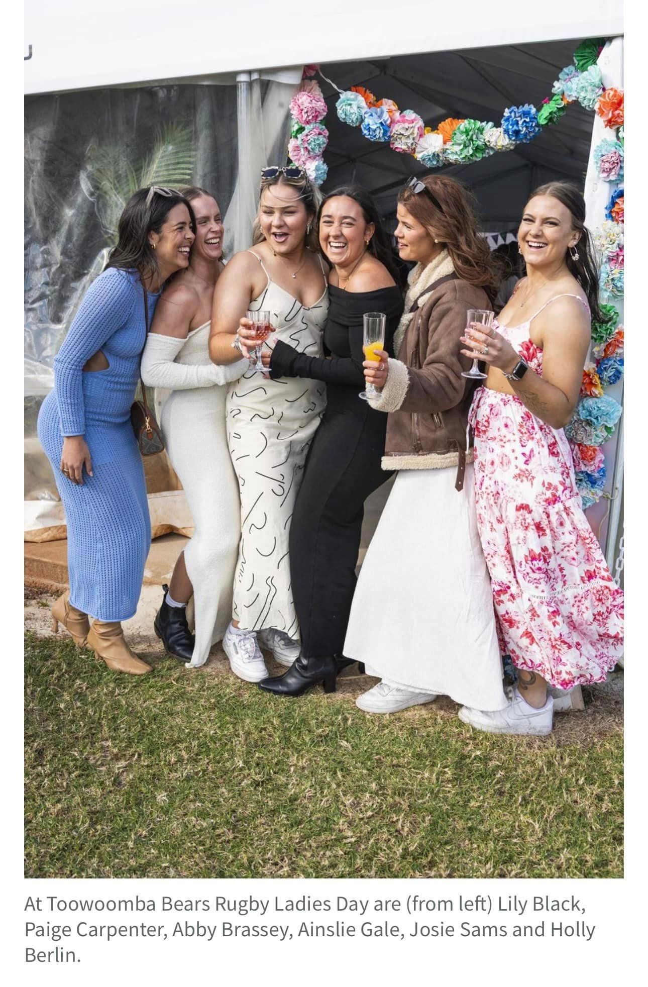 A group of women in dresses are posing for a picture.