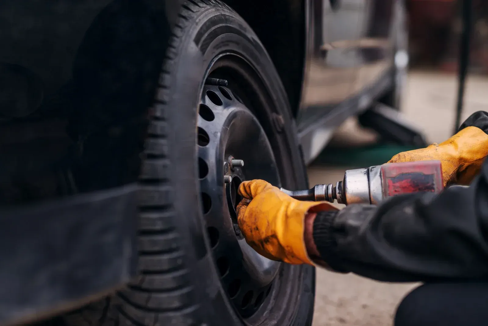 A man is changing a tire on a car with a wrench.