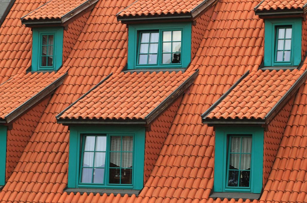 A row of houses with red tile roofs and green windows.