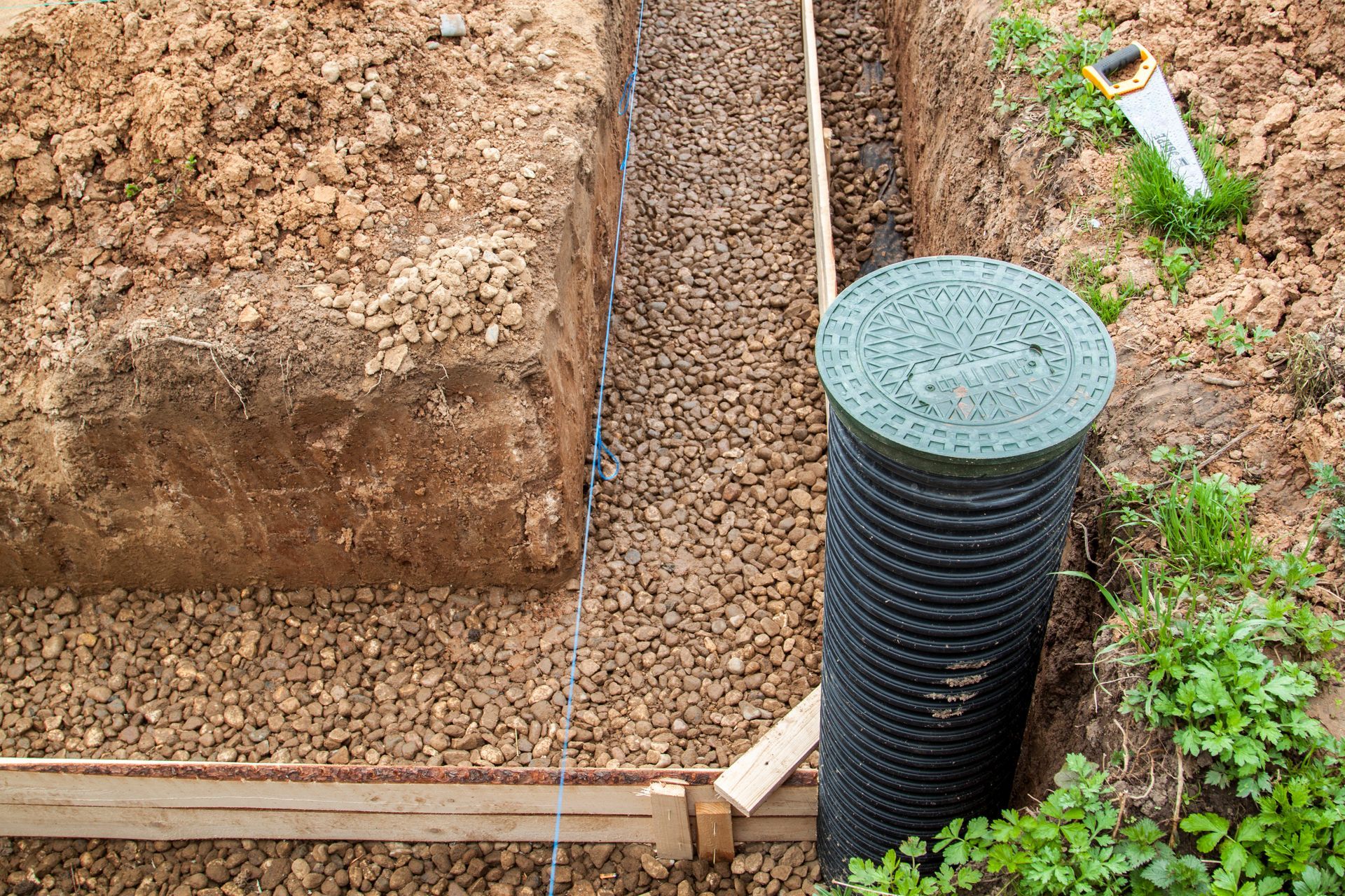 A drain pipe is being installed in a hole in the ground.