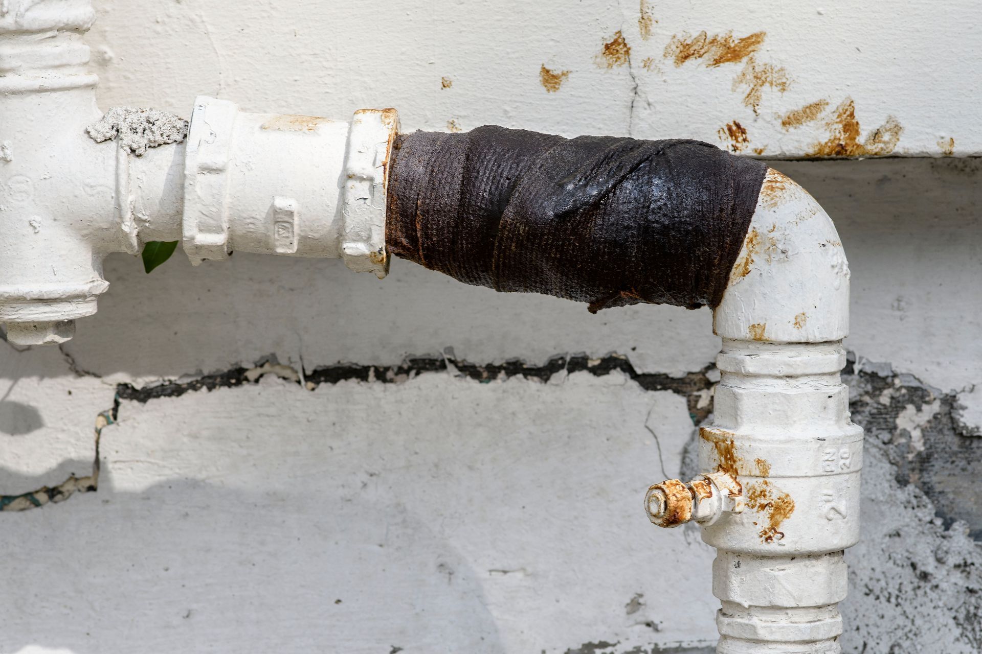 A close up of a white pipe with rust on it.