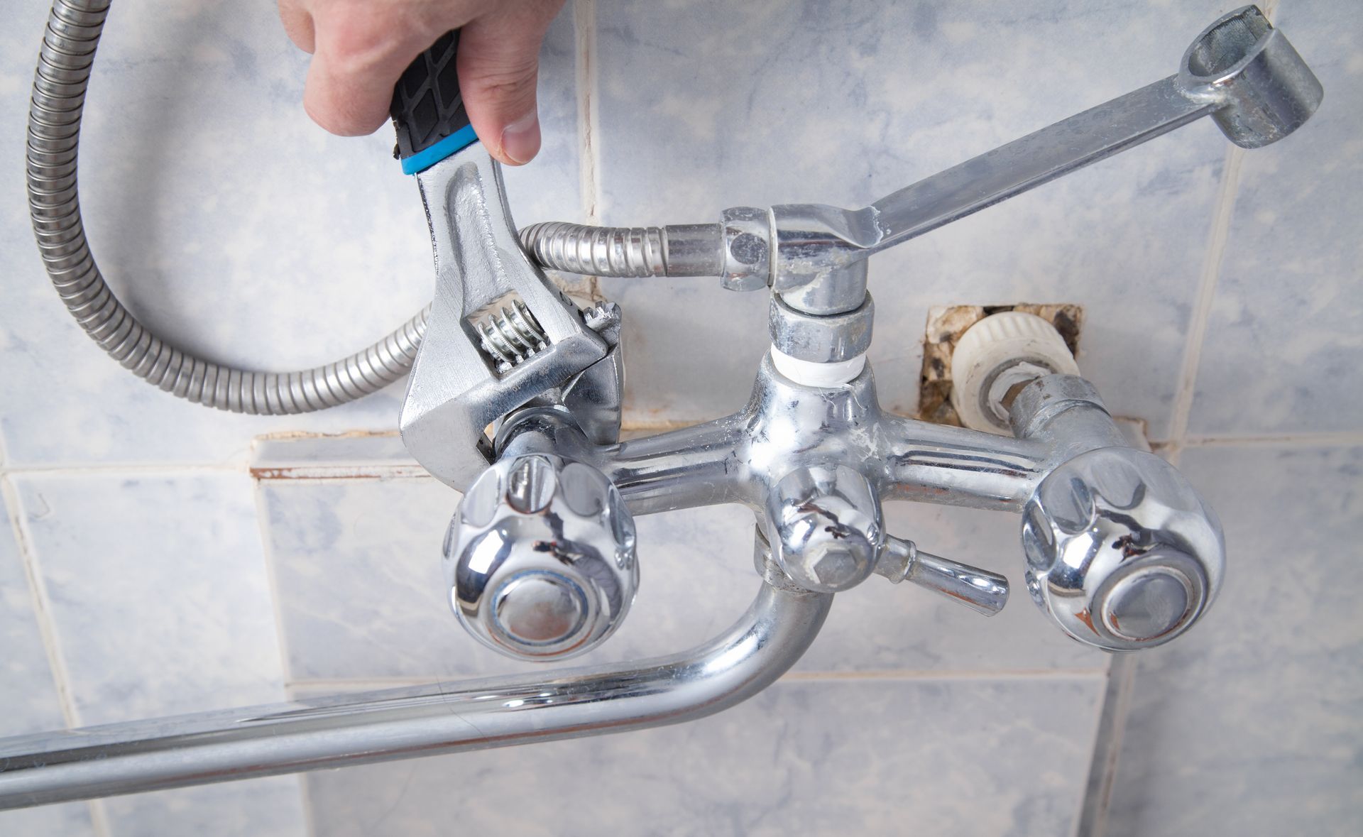 A person is fixing a shower head with a wrench.