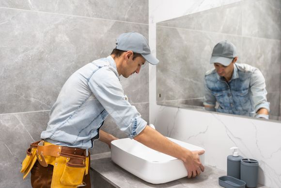 A man is fixing a sink in a bathroom.