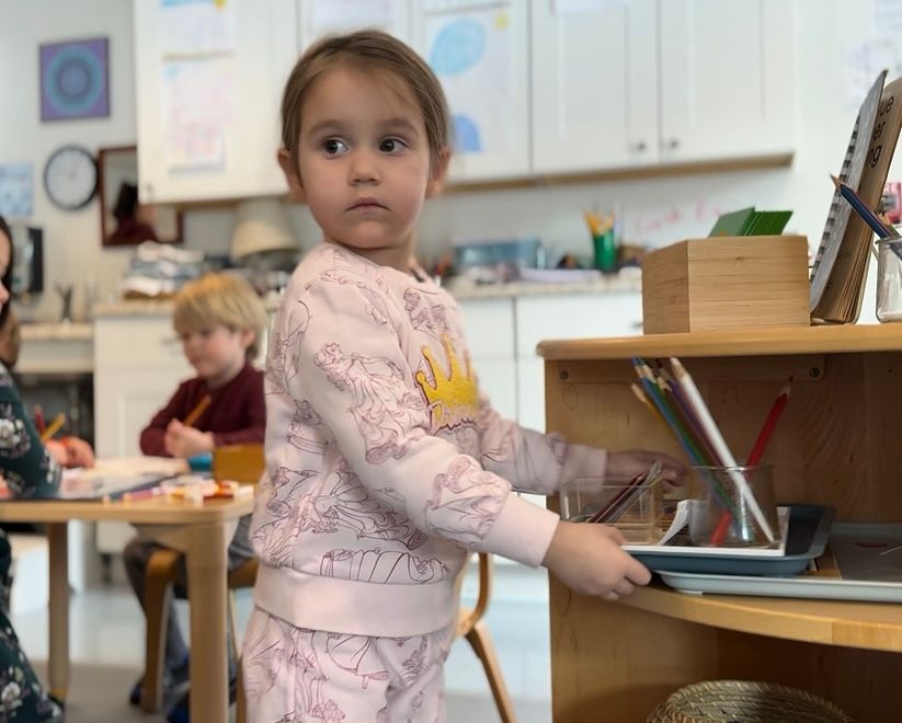 A group of children are working in a montessori classroom with tower of wooden cubes.