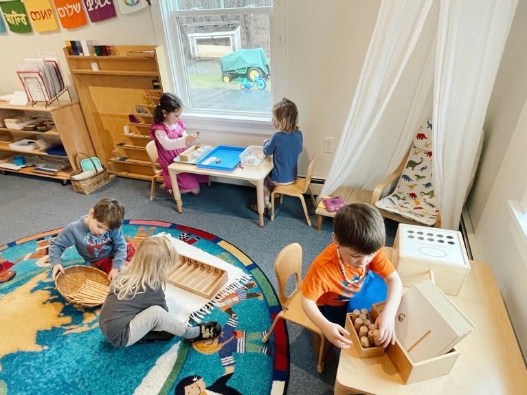 A group of children are in their montessori classroom working on their lessons