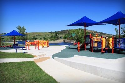 A playground with blue umbrellas and a lake in the background