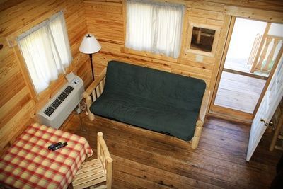 An aerial view of a living room in a cabin with a couch , table and chairs.