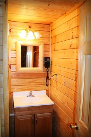 A bathroom in a log cabin with a sink , mirror and hair dryer.