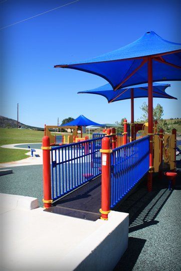A playground with blue umbrellas and a ramp