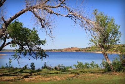 A lake with trees in the foreground and a blue sky in the background