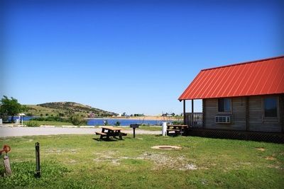 A small house with a red roof and a picnic table in front of it.