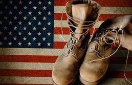 A pair of military boots sitting on top of an american flag.