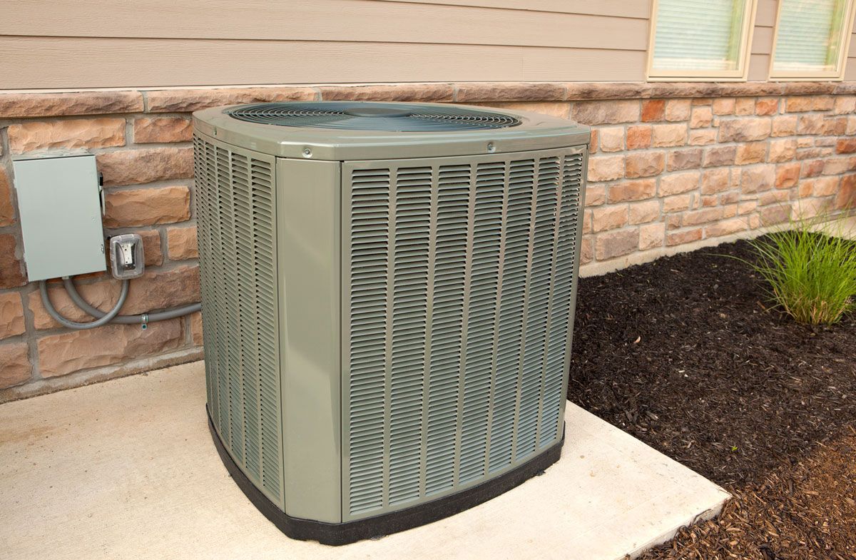 An air conditioner is sitting on the side of a brick building.