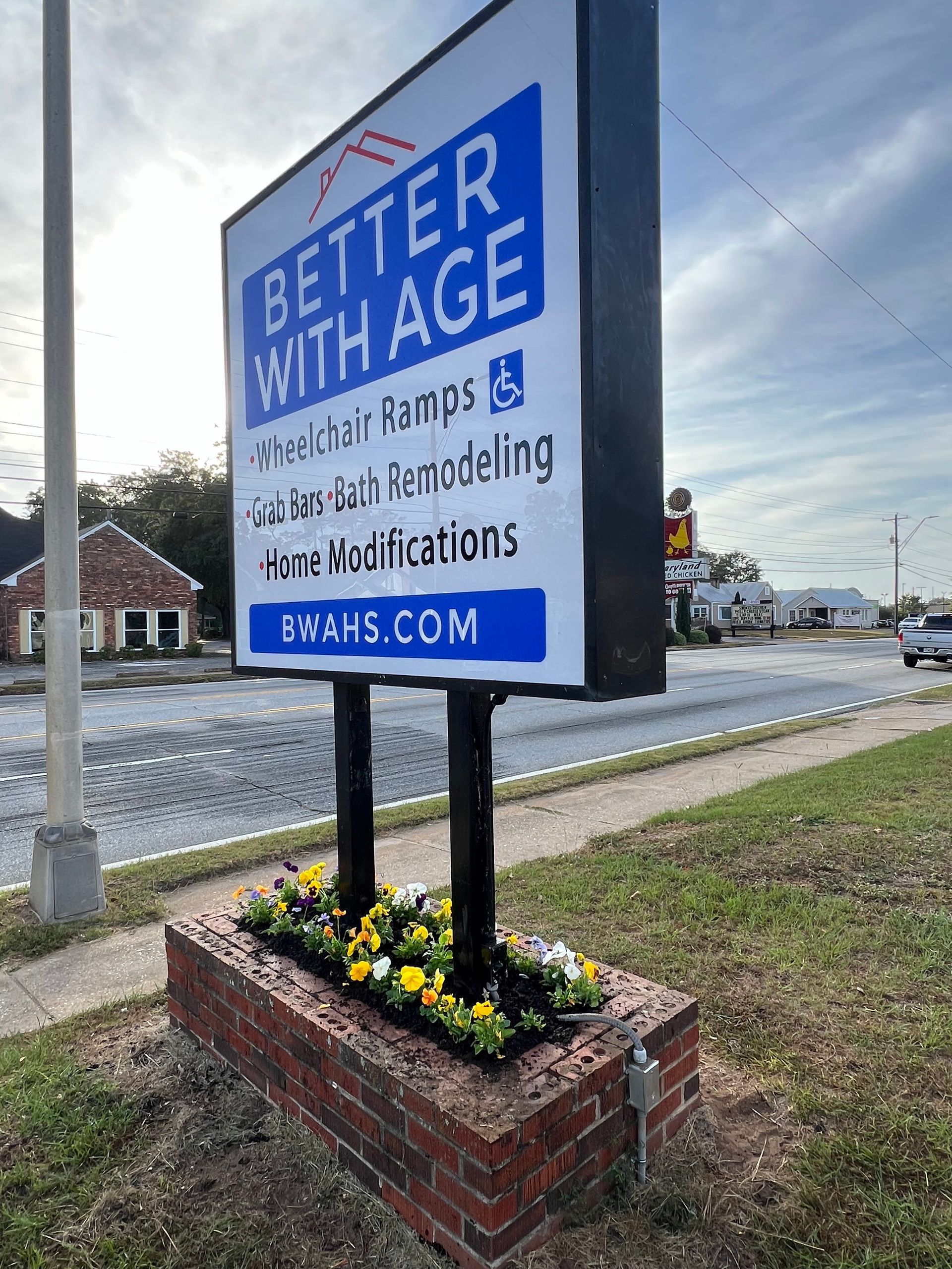 A sign for better with age is sitting on the side of the road.
